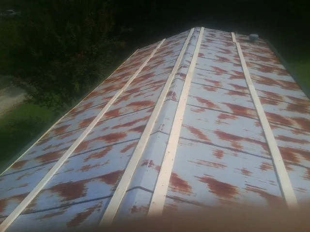 Rusted metal roof panels with new wood purlins before replacement — Storm Damage Roof Repair in Humphrey by Roofing Brothers