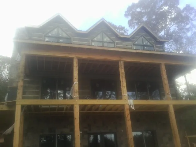 Dormers and porch framing on a large log home under construction — Roof Coating work by our crew in Humphrey