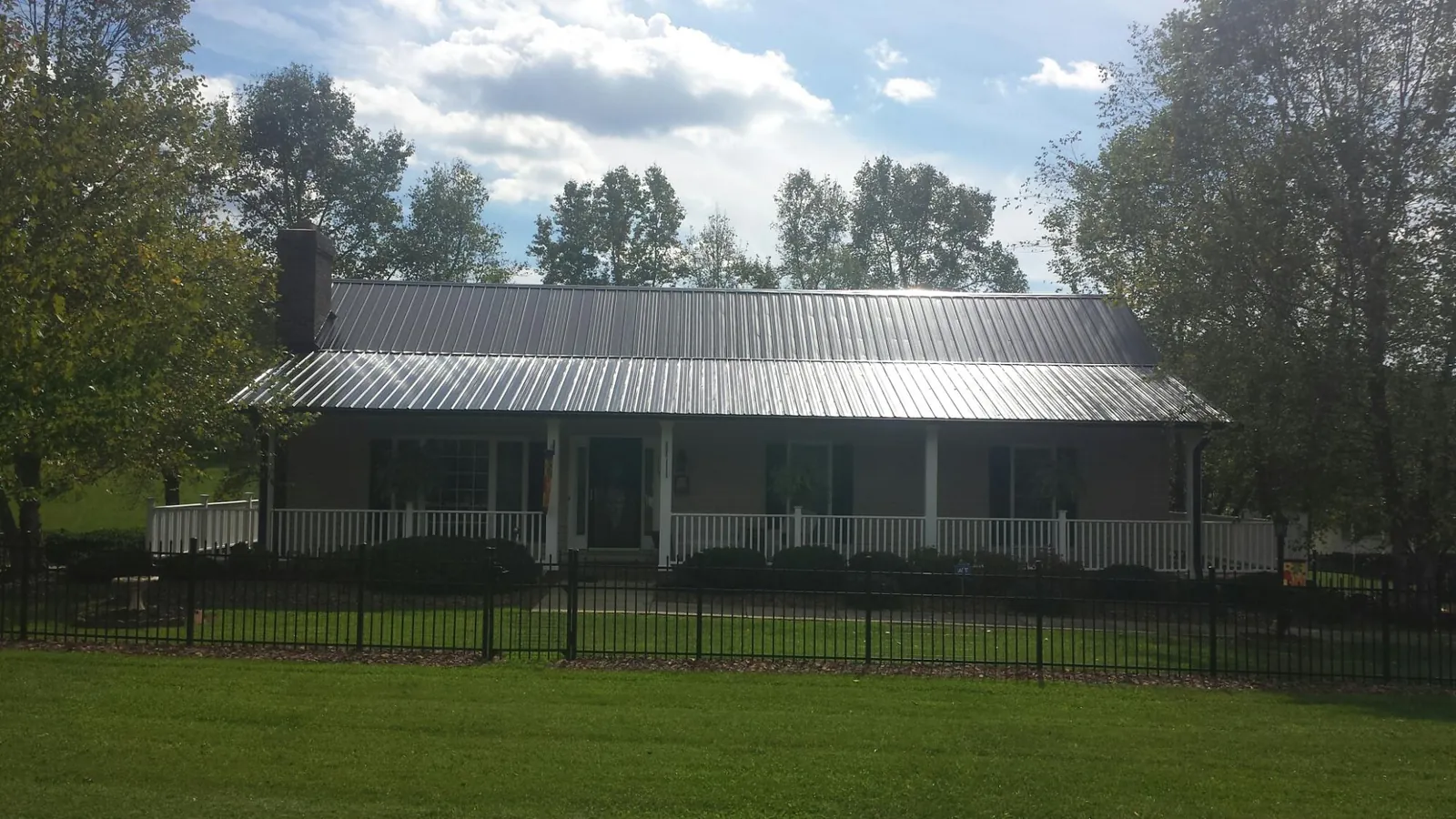 Gray metal roof on a brick ranch with a full width front porch — Gutter Guard Installation work by our crew in Humphrey