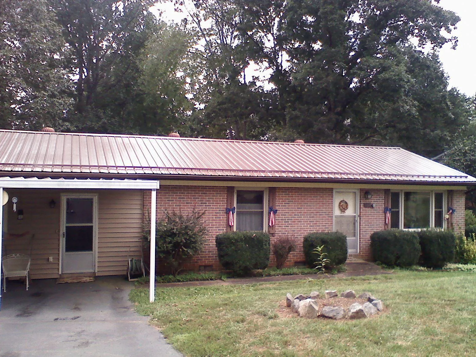Bronze metal roof and carport on a brick ranch home — Roof Repair work by our crew in Humphrey