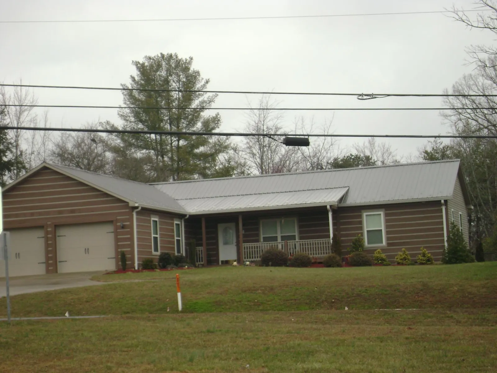 Gray metal roof on a log sided ranch home with a front porch in Humphrey